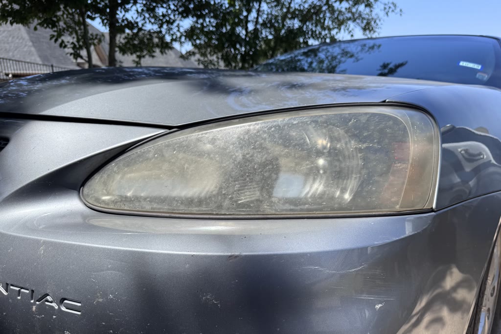 Cloudy and weathered Pontiac headlight before exterior restoration